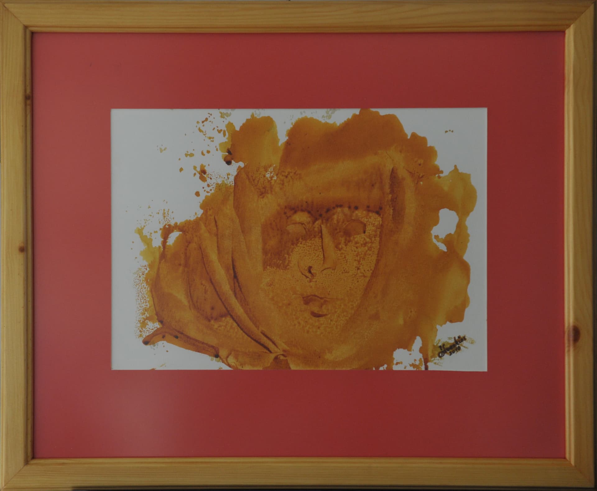 Face surrounded by draped folds formed within a golden-brown wash blot on paper mounted on a terracotta mat in a light wood frame