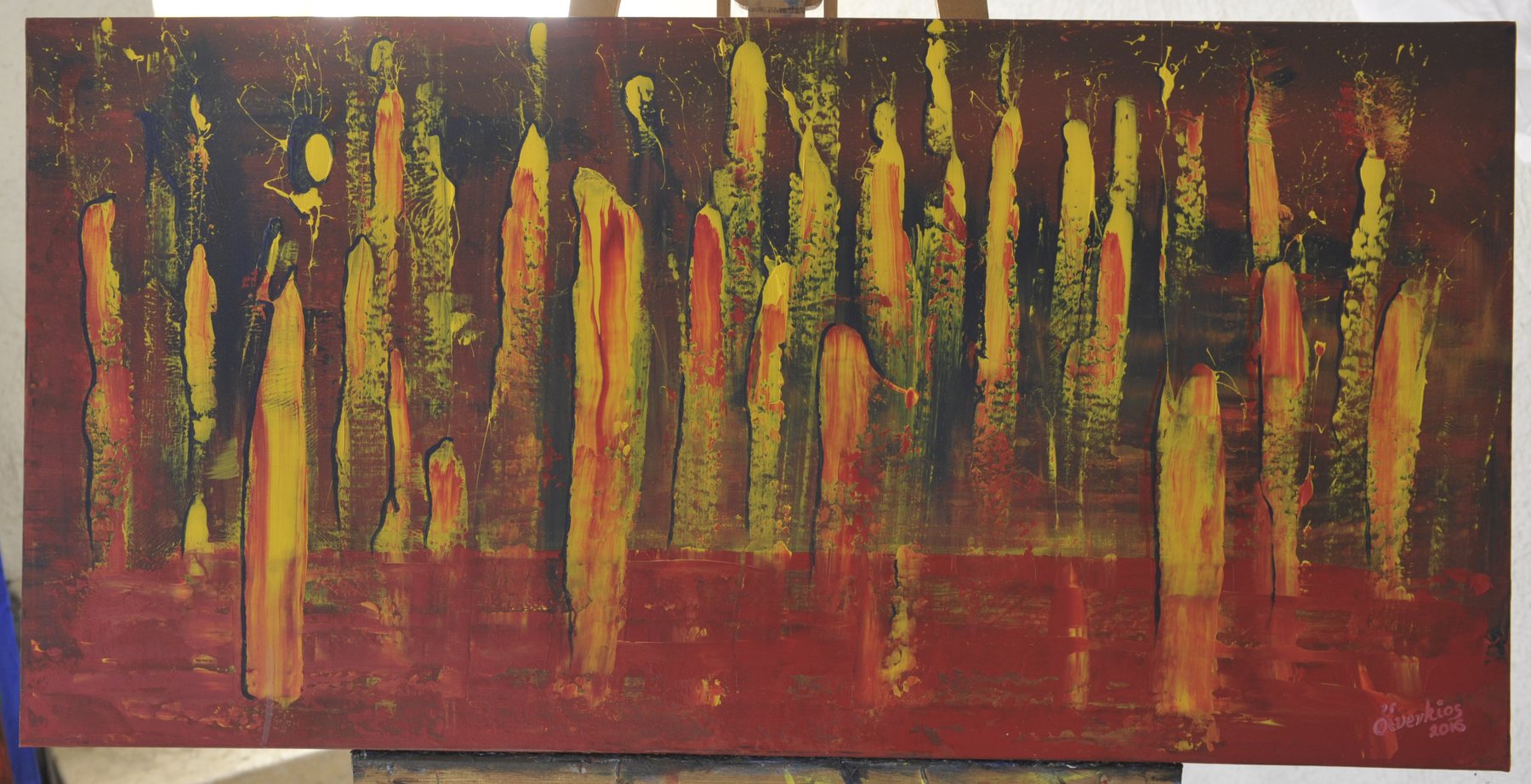 Wide landscape abstract painting with elongated vertical yellow and orange strokes and fine drips above a solid red field