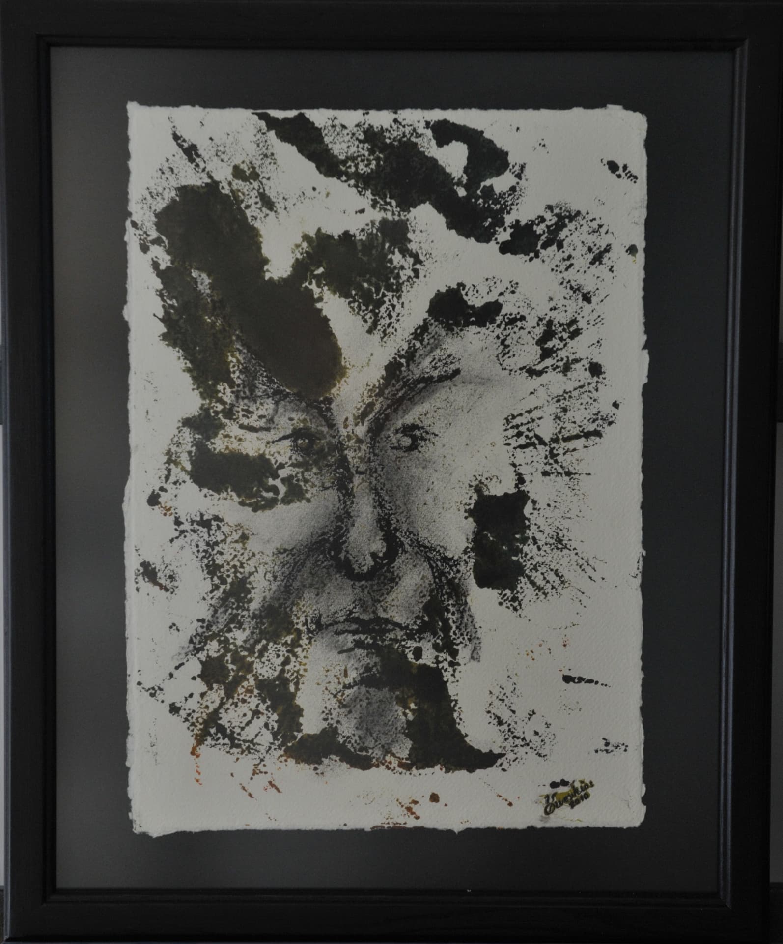 Face emerging from splattered and pooled dark ink on cream paper, on deckle-edged paper mounted on a charcoal mat