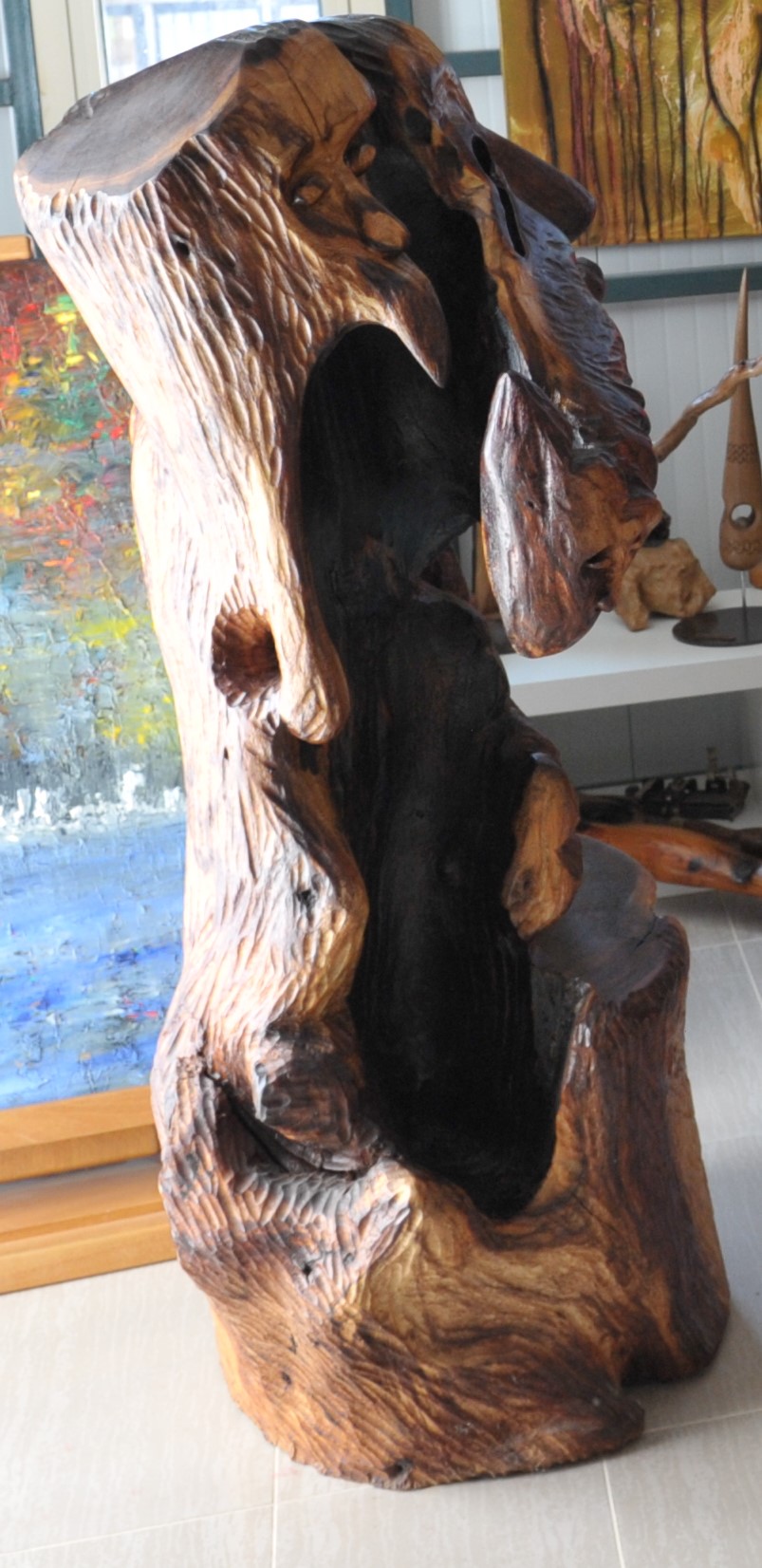 Tall irregular wood sculpture with a large dark hollow and polished edges