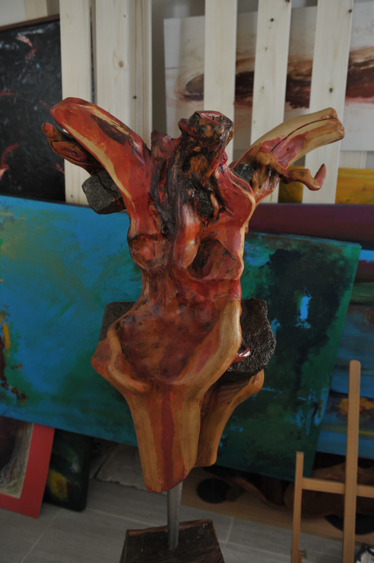 Reddish branching wood carving with a central figure in a studio