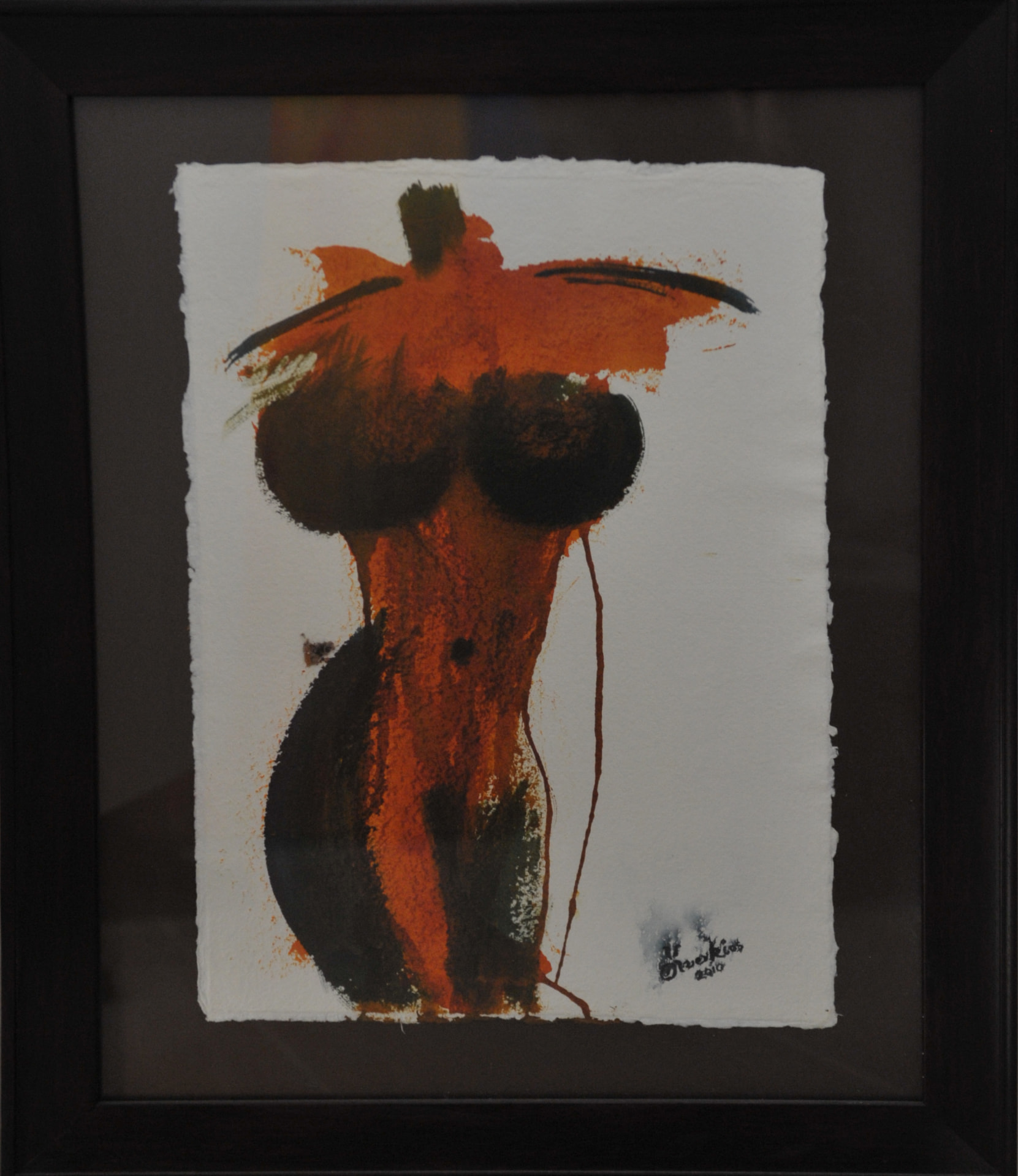 Painting of a standing female figure in burnt orange and dark olive brushwork over white deckle-edged paper, in a dark wooden frame