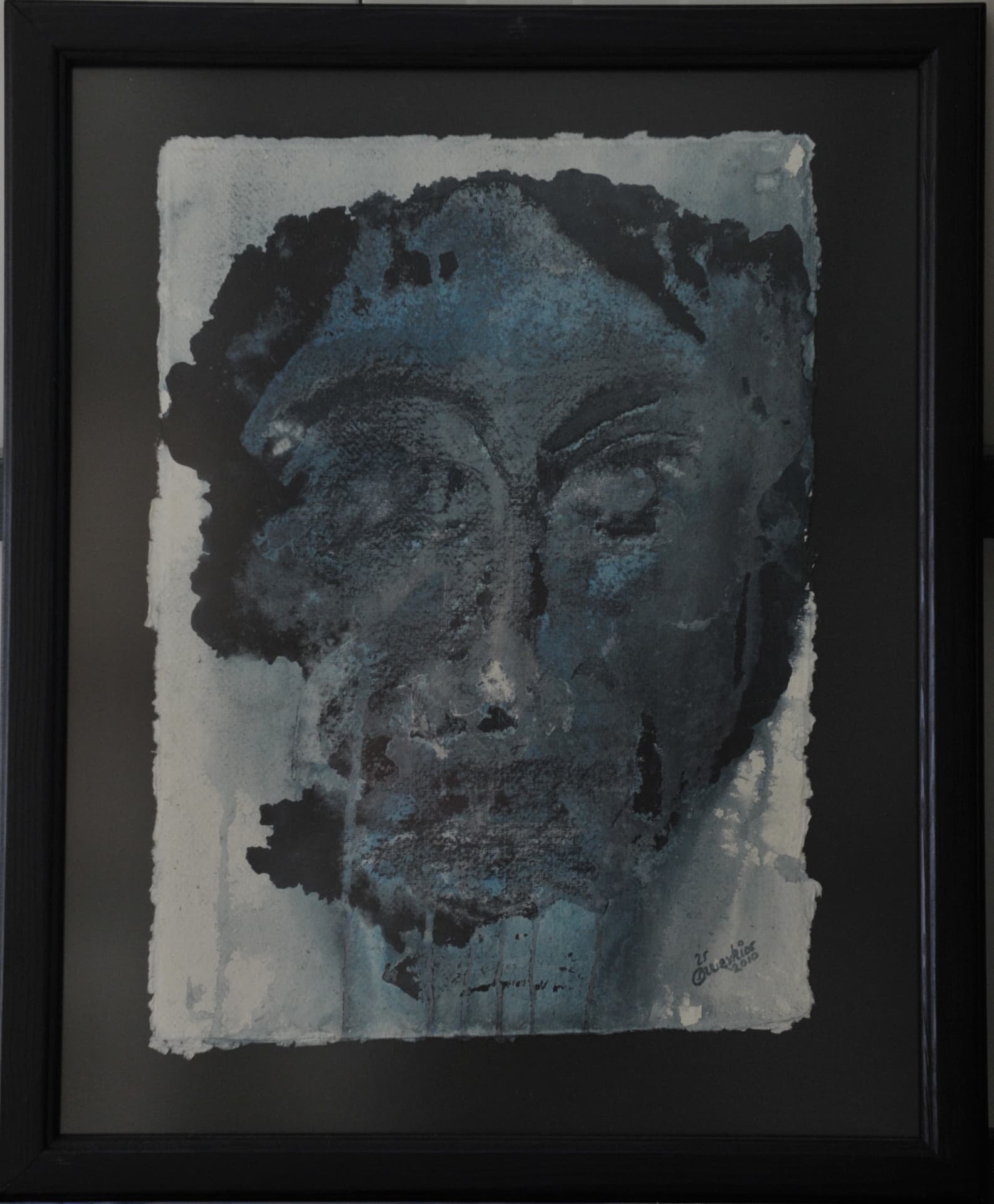 Semi-abstract face with closed eyes and paint drips running down the chin, in slate blue, grey and black on paper mounted on a dark mat