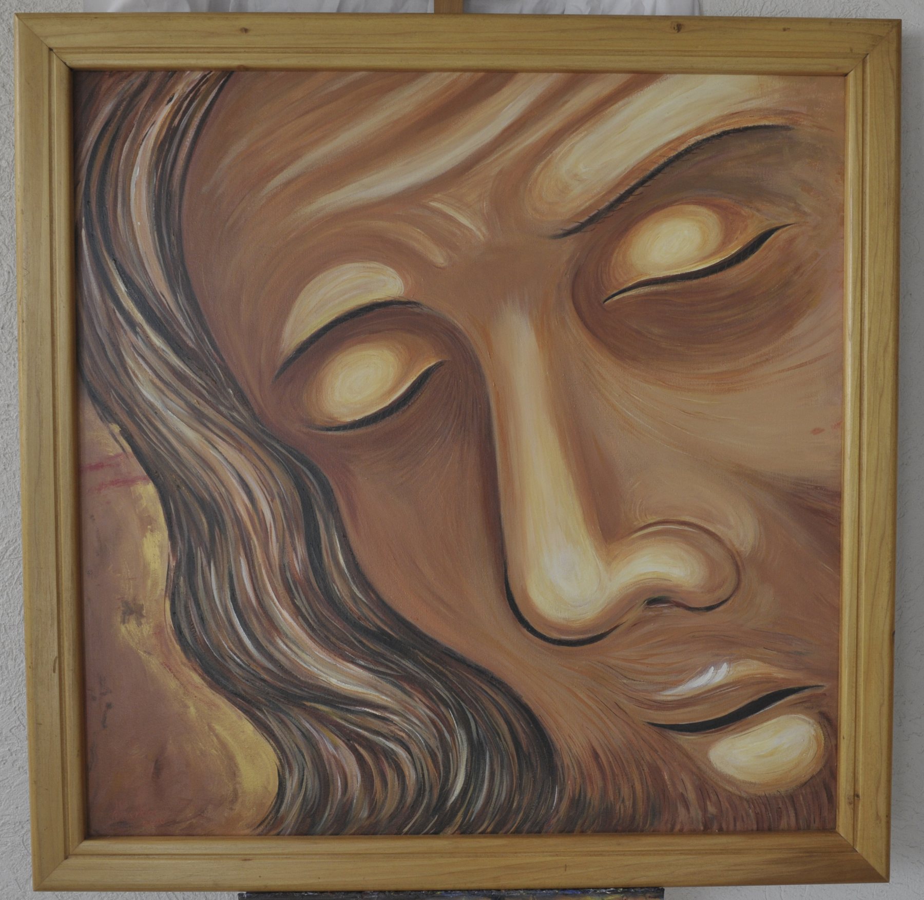 Painting of a face with closed eyes in warm ochre tones, in a wooden frame