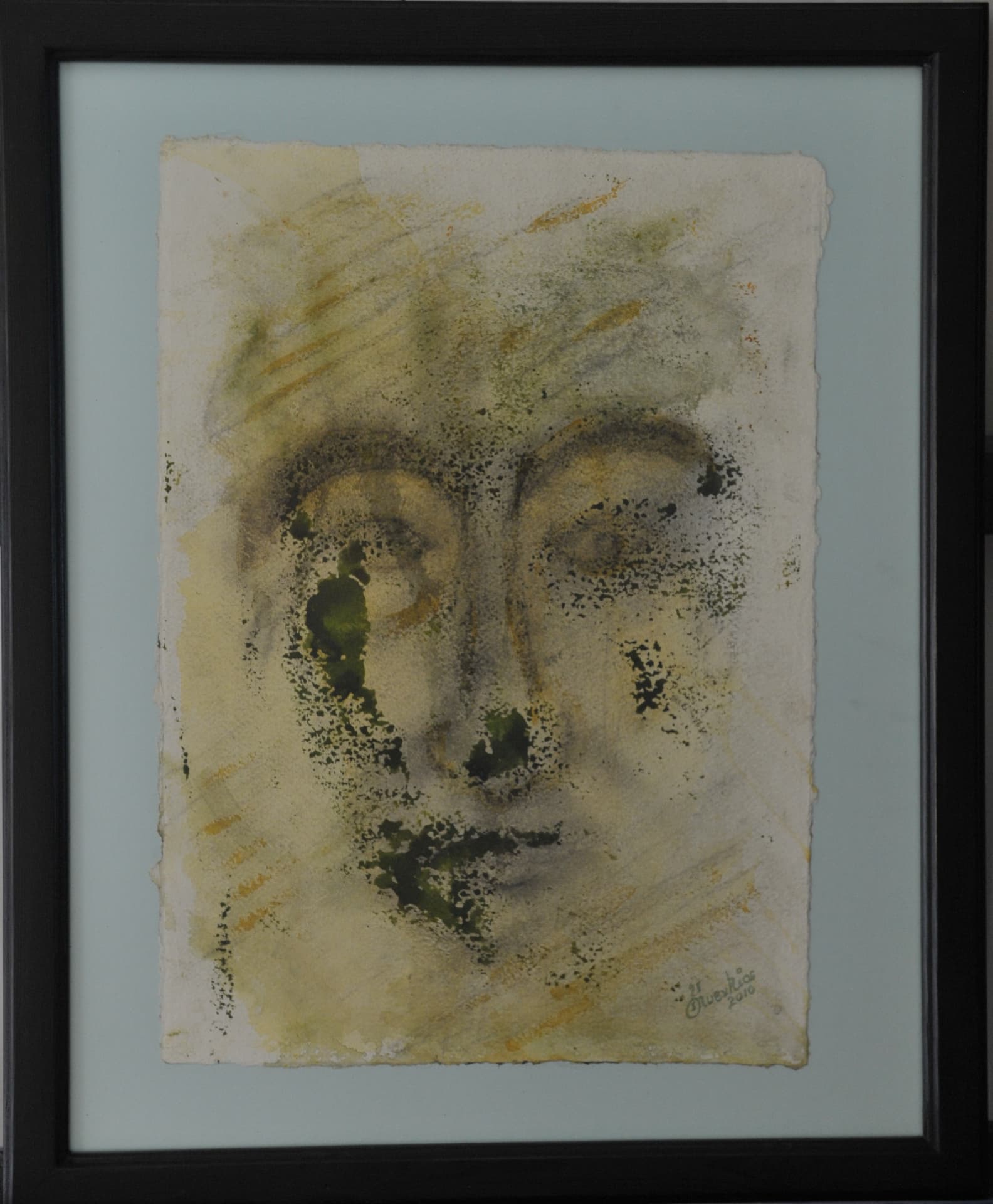Faint face with arched brows and shaded eyes, in pale ochre and olive pigment with smudged charcoal on deckle-edged paper mounted on a pale grey-blue mat