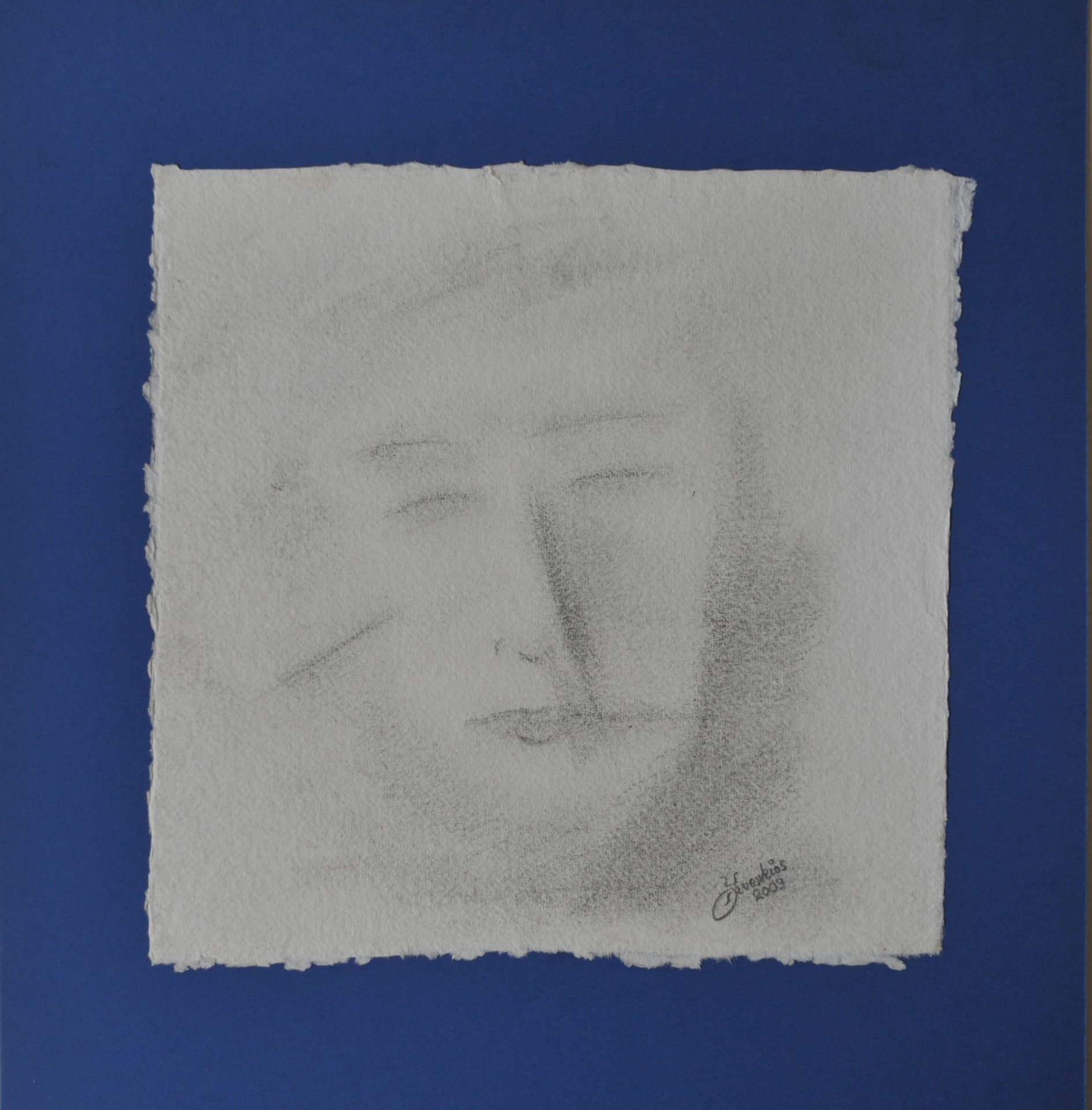 Very faint face in soft smudged grey charcoal on deckle-edged paper mounted on a blue mat