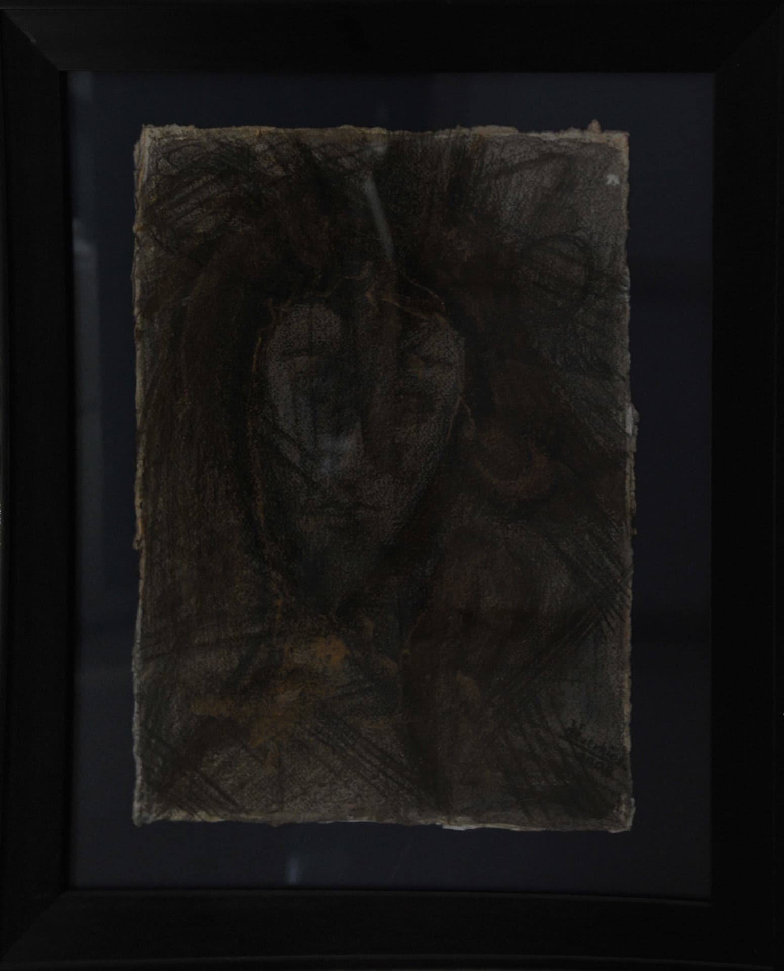 Shadowed face surrounded by dense dark strokes and cross-hatching on deckle-edged paper mounted on a black mat