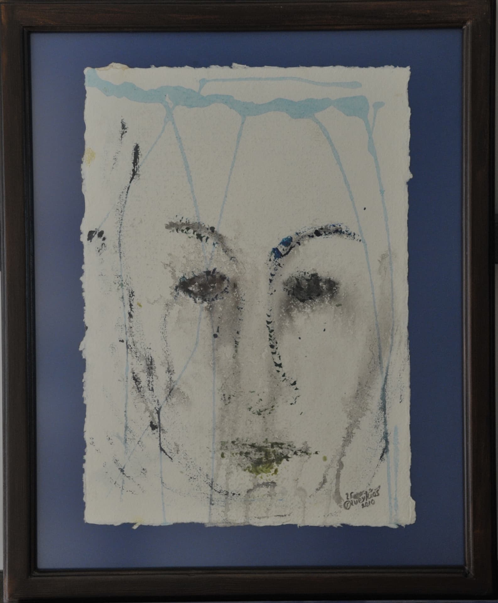 Minimal face in grained black marks with pale blue drips running from the top edge, on deckle-edged paper mounted on a slate-blue mat