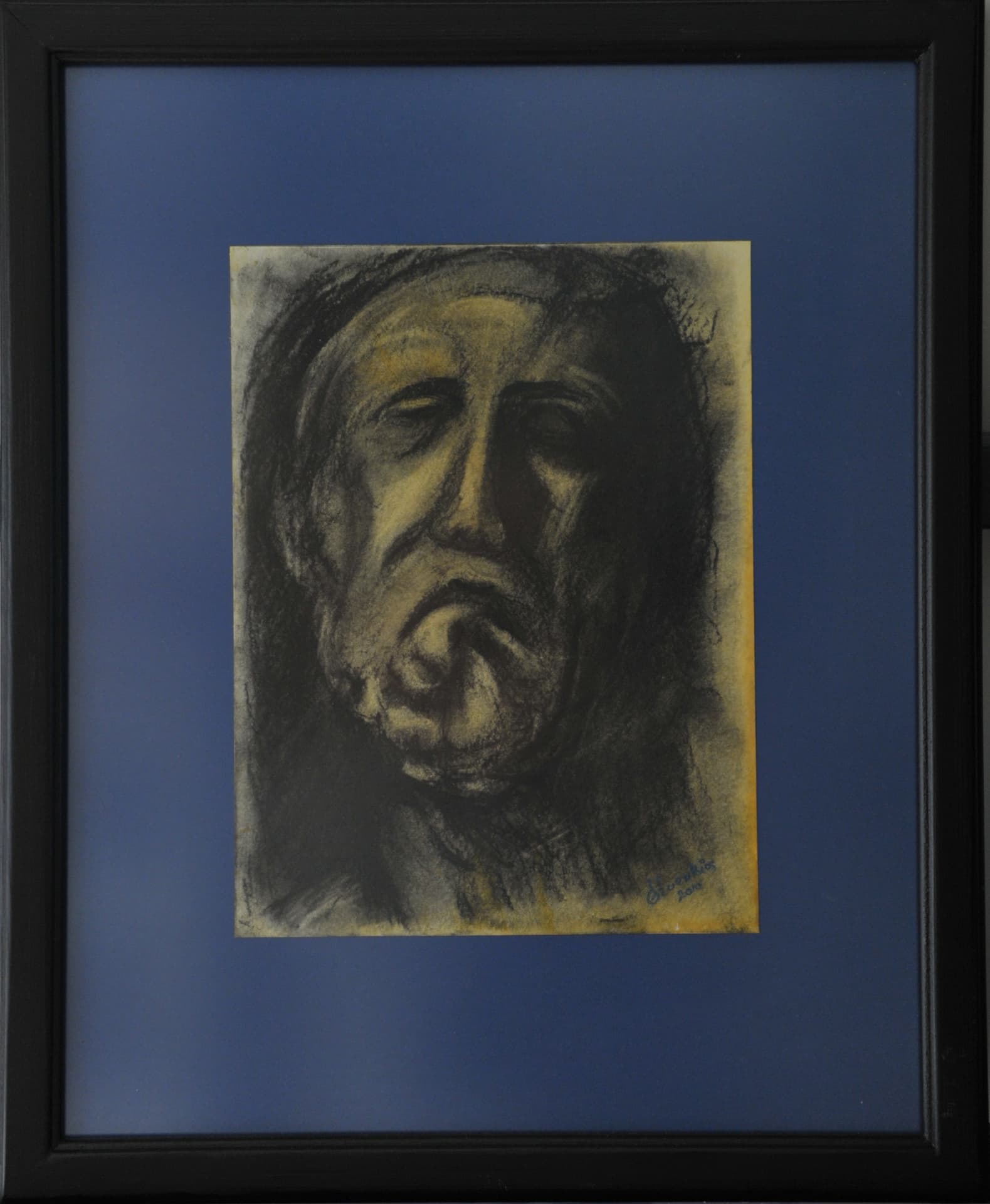 Expressive contorted face in charcoal and chalk on ochre-toned paper, mounted on a blue mat