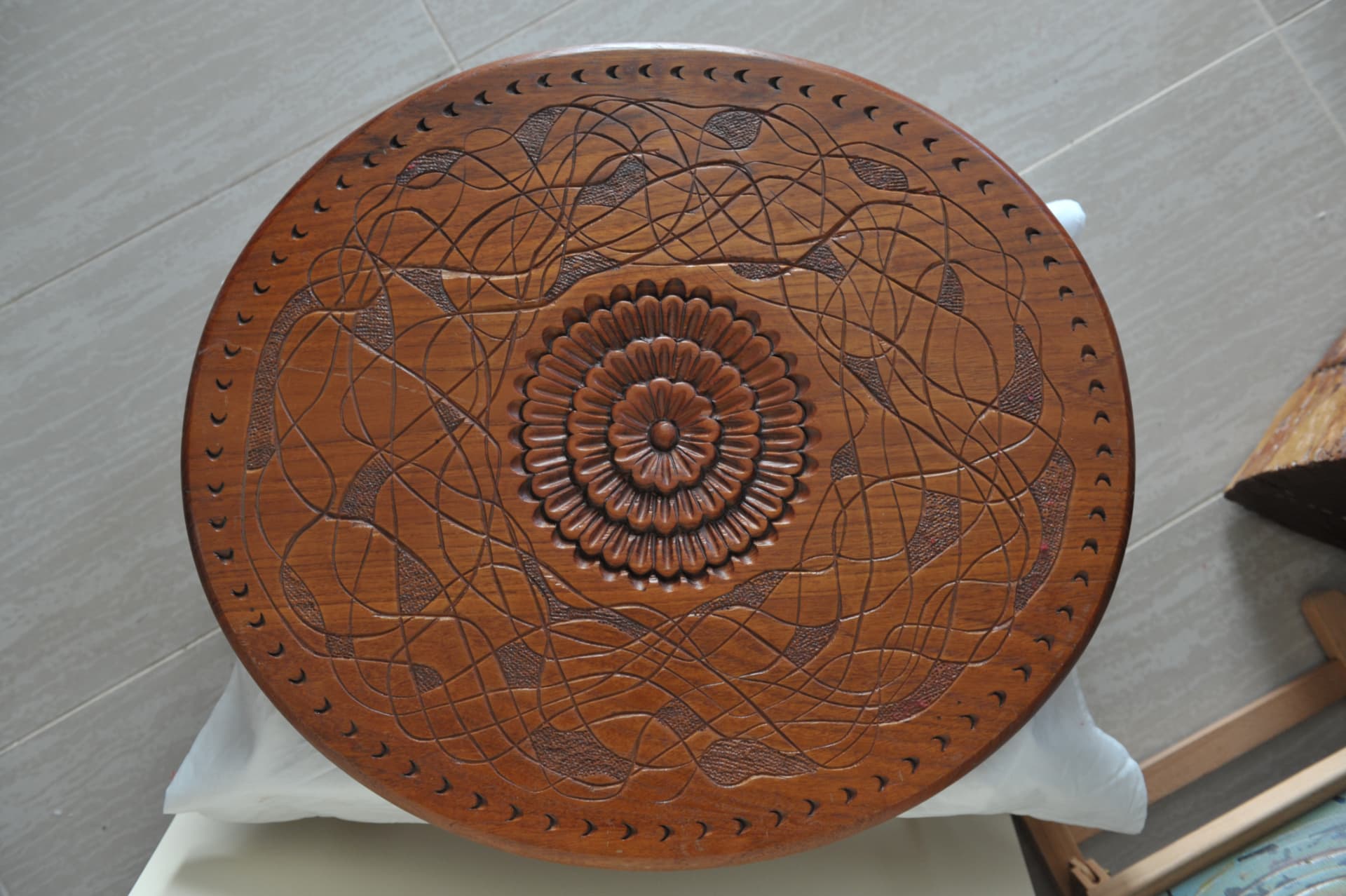 Circular wood carving with concentric geometric and floral patterns