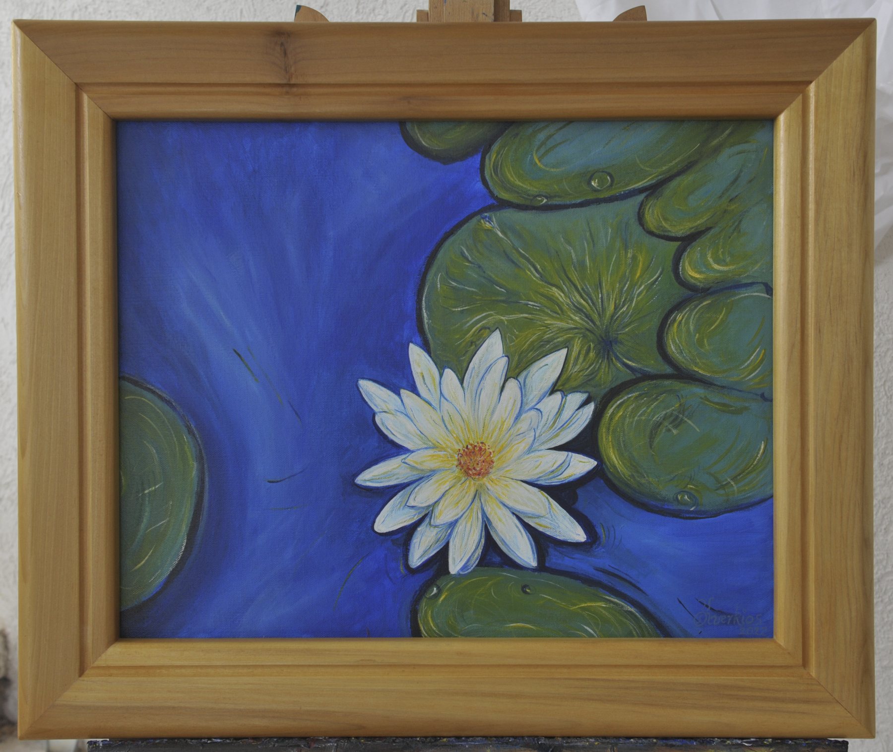 Painting of a white water lily with a yellow centre and green pads on deep blue water, in a wooden frame
