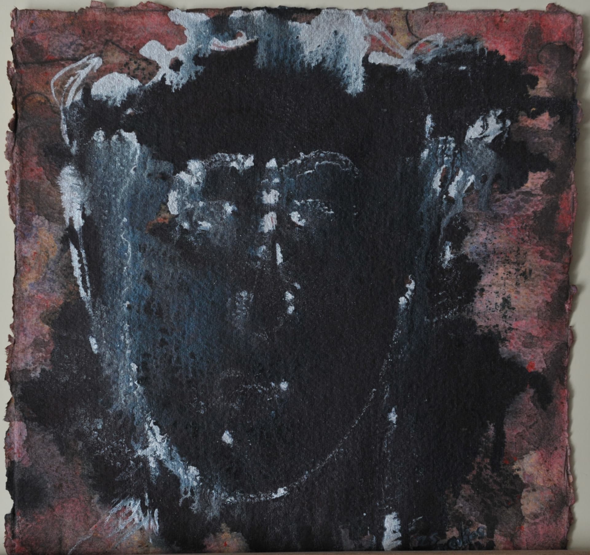 Dark face with white highlights amid black ink and deep red washes, on deckle-edged paper